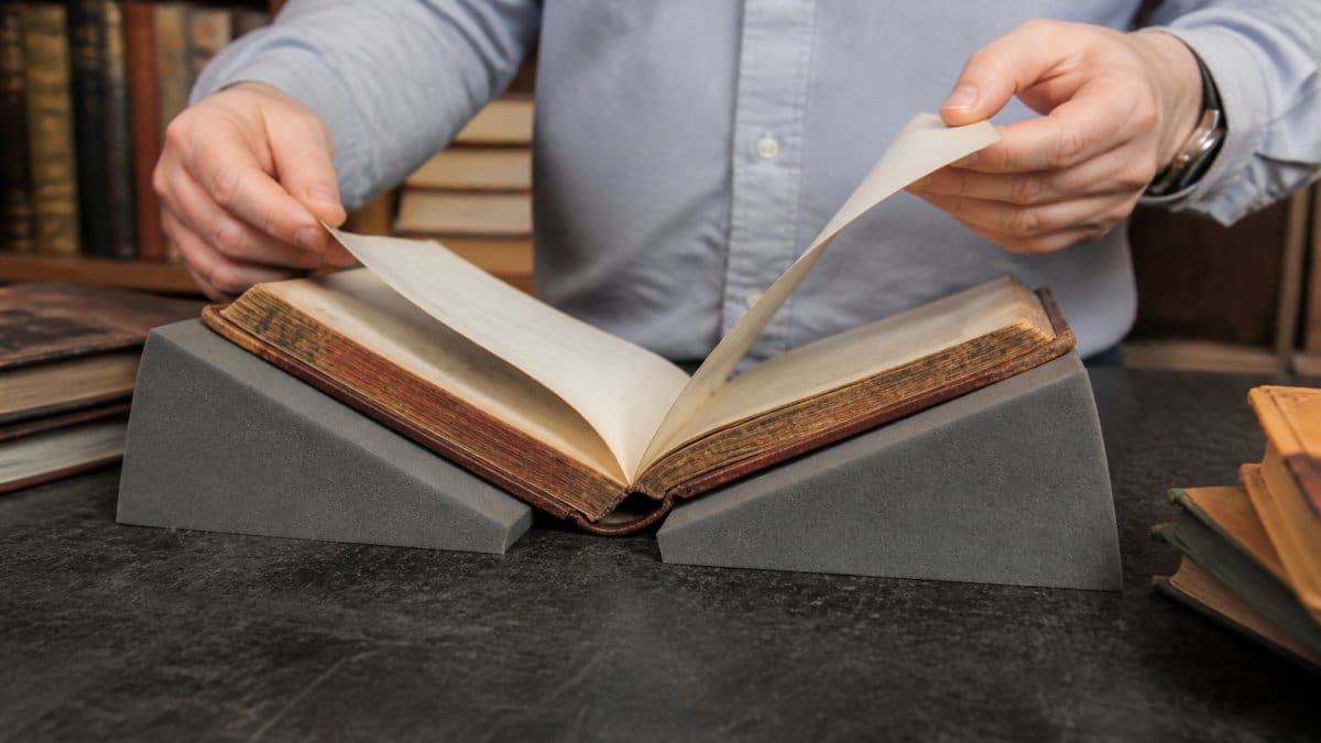 Diagram demonstrating how to use a book cradle to preserve antique book collections by supporting pages safely